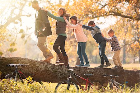 following - Family walking in a row on fallen log near bicycles Stock Photo - Premium Royalty-Free, Code: 6124-08170353