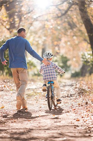 parent teaching outdoor - Father teaching son to ride bicycle on path in woods Stock Photo - Premium Royalty-Free, Code: 6124-08170386