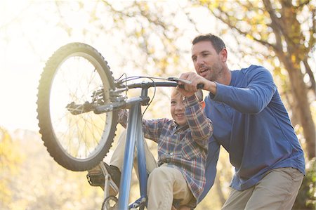 family dad - Father teaching son wheelie on bicycle Stock Photo - Premium Royalty-Free, Code: 6124-08170441