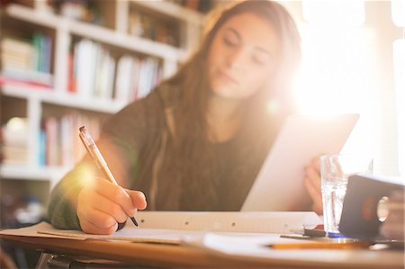 Teenage girl with digital tablet doing homework at sunny desk Stock Photo - Premium Royalty-Free, Code: 6124-08170467