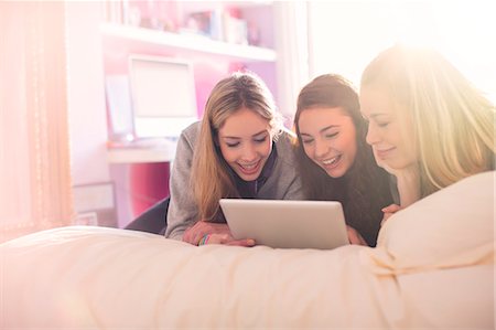 simsearch:6124-08170465,k - Teenage girls using digital tablet on bed in sunny bedroom Fotografie stock - Premium Royalty-Free, Codice: 6124-08170487