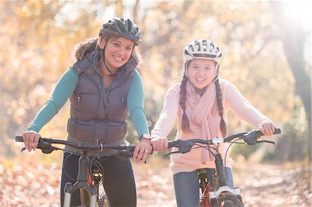 daughter riding on mother - Portrait of smiling mother and daughter on mountain bikes in woods Stock Photo - Premium Royalty-Free, Code: 6124-08170401