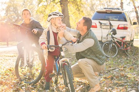 Father fastening helmet of son on bicycle in autumn woods Stock Photo - Premium Royalty-Free, Code: 6124-08170402