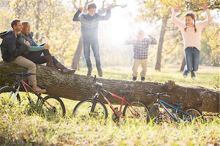 father playing kids - Family playing on fallen log with bicycles in woods Stock Photo - Premium Royalty-Free, Code: 6124-08170424