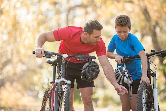 Father and son examining wheel on mountain bike Stock Photo - Premium Royalty-Free, Image code: 6124-08170434