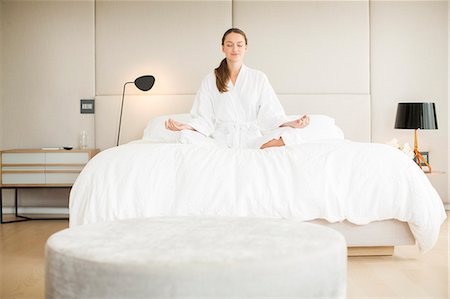 simsearch:693-03312809,k - Serene woman in bathrobe meditating in lotus position on bed Foto de stock - Sin royalties Premium, Código: 6124-08170517