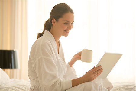 Woman in bathrobe drinking coffee and using digital tablet in bedroom Stock Photo - Premium Royalty-Free, Code: 6124-08170526