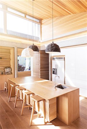 Modern pendant lights hanging over wooden kitchen island Photographie de stock - Premium Libres de Droits, Code: 6124-08170641