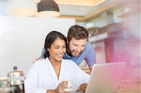 simsearch:6113-07565759,k - Laughing couple drinking coffee and using laptop Stock Photo - Premium Royalty-Free, Code: 6124-08170644