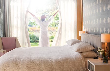 simsearch:6124-08170697,k - Woman in bathrobe opening bedroom curtains Foto de stock - Sin royalties Premium, Código: 6124-08170665