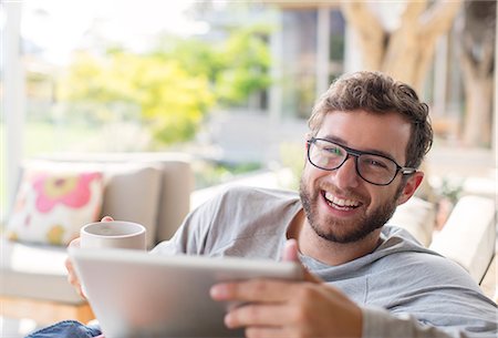 person on computer - Portrait smiling man drink coffee and using digital tablet Stock Photo - Premium Royalty-Free, Code: 6124-08170601