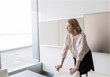 Pensive businesswoman looking out office window Foto de stock - Sin royalties Premium, Código: 6124-08520395