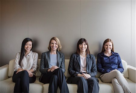 simsearch:6113-08184304,k - Portrait smiling businesswomen sitting in a row on sofa Photographie de stock - Premium Libres de Droits, Code: 6124-08520403