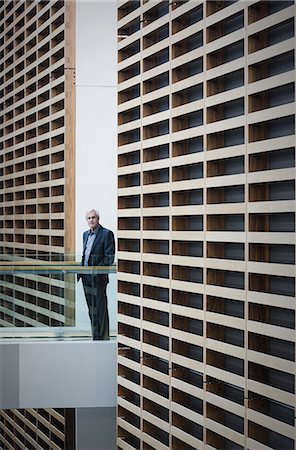 Portrait senior businessman on walkway in modern office Stock Photo - Premium Royalty-Free, Code: 6124-08520401