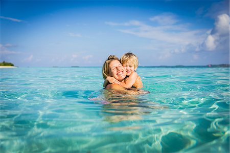 Enthusiastic mother hugging son in tropical ocean Photographie de stock - Premium Libres de Droits, Code: 6124-08658144