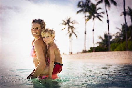 devoted - Portrait smiling mother piggybacking son in tropical ocean Stock Photo - Premium Royalty-Free, Code: 6124-08658148