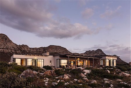 Home showcase exterior on craggy hillside under clouds at dusk Photographie de stock - Premium Libres de Droits, Code: 6124-08658113