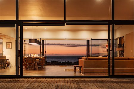 Illuminated home showcase interior overlooking ocean at sunset Foto de stock - Sin royalties Premium, Código: 6124-08658119