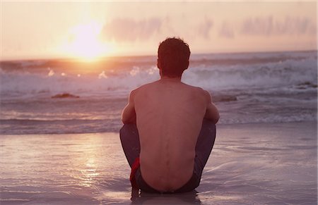 sit man backside view - Pensive young man on beach watching sunset over ocean Stock Photo - Premium Royalty-Free, Code: 6124-08658135
