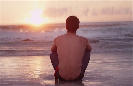 surf sunset - Pensive young man on beach watching sunset over ocean Stock Photo - Premium Royalty-Free, Code: 6124-08658135