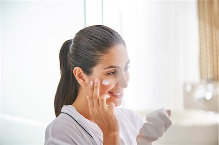 Woman applying face cream to cheek Photographie de stock - Premium Libres de Droits, Code: 6124-08743243