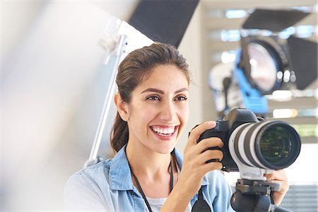 Smiling female photographer behind camera in studio Foto de stock - Sin royalties Premium, Código: 6124-08743259