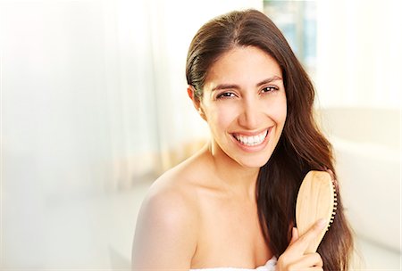 simsearch:6124-08743296,k - Portrait smiling brunette woman brushing hair Photographie de stock - Premium Libres de Droits, Code: 6124-08743263