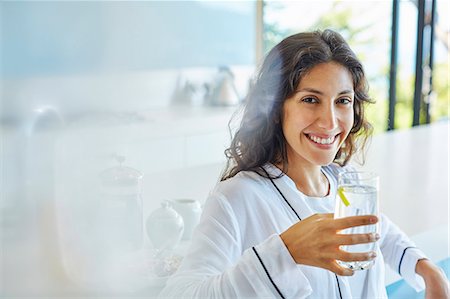 drinking glass of water - Portrait smiling woman in bathrobe drinking water in kitchen Stock Photo - Premium Royalty-Free, Code: 6124-08743298