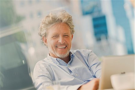 Portrait smiling businessman using digital tablet at sidewalk cafe Stock Photo - Premium Royalty-Free, Code: 6124-08743225