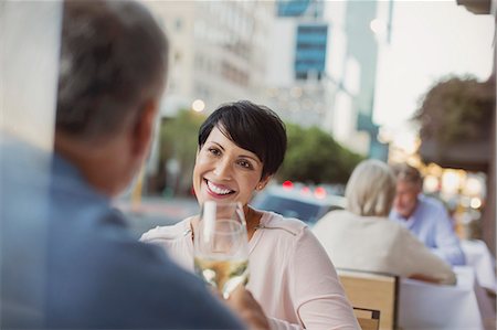 Smiling couple toasting white wine glasses at urban sidewalk cafe Foto de stock - Sin royalties Premium, Código: 6124-08743235