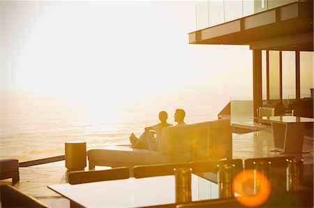 Silhouette couple relaxing on chaise lounge enjoying sunset ocean view Stock Photo - Premium Royalty-Free, Code: 6124-08743367