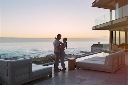 Affectionate couple hugging on luxury patio with ocean view Photographie de stock - Premium Libres de Droits, Code: 6124-08743307