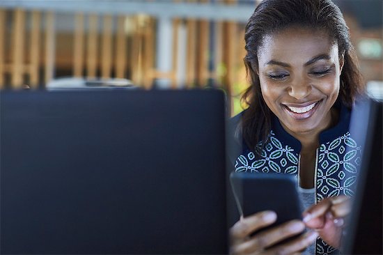 Smiling businesswoman texting with cell phone Stock Photo - Premium Royalty-Free, Image code: 6124-08768354