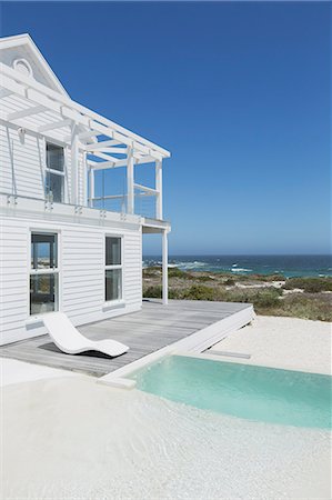 simsearch:6113-06898661,k - White beach house and swimming pool with ocean view under sunny blue sky Fotografie stock - Premium Royalty-Free, Codice: 6124-08703858