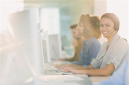 Portrait smiling businesswoman with headset working at computer in office Photographie de stock - Premium Libres de Droits, Code: 6124-08703892