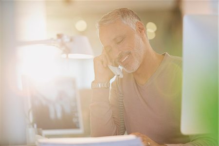 Businessman talking on telephone in sunny office Stock Photo - Premium Royalty-Free, Code: 6124-08703903