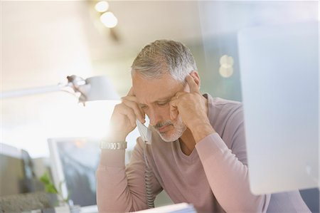 Serious businessman talking on telephone in office Stock Photo - Premium Royalty-Free, Code: 6124-08703910