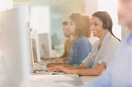 Smiling businesswoman with headset working at computer in office Foto de stock - Sin royalties Premium, Código: 6124-08703921