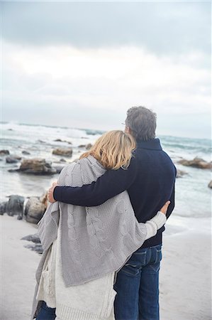 Serene affectionate couple hugging on winter beach looking at ocean Stock Photo - Premium Royalty-Free, Code: 6124-08805243