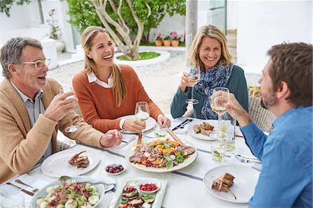 Couples laughing, drinking white wine and eating lunch at patio table Stock Photo - Premium Royalty-Free, Code: 6124-08805244