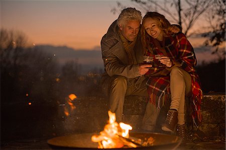 simsearch:6109-08945043,k - Couple drinking enjoying autumn campfire Foto de stock - Sin royalties Premium, Código: 6124-08820692