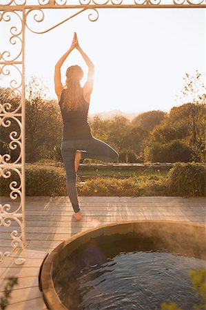 Woman practicing yoga tree pose on patio with hot tub and autumn tree view Stock Photo - Premium Royalty-Free, Code: 6124-08820699
