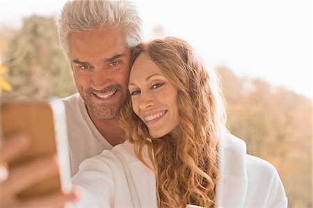 simsearch:6113-07242668,k - Affectionate couple smiling taking selfie with camera phone outdoors Stock Photo - Premium Royalty-Free, Code: 6124-08820752