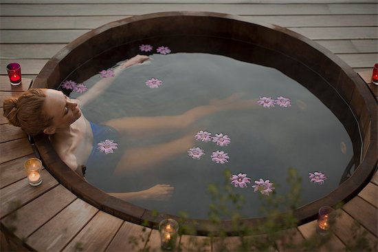 Serene woman soaking in hot tub with flowers and candles on patio Foto de stock - Sin royalties Premium, Código de la imagen: 6124-08820759