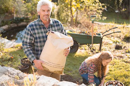 simsearch:632-02690351,k - Portrait couple gardening holding potting soil in autumn garden Stock Photo - Premium Royalty-Free, Code: 6124-08820706