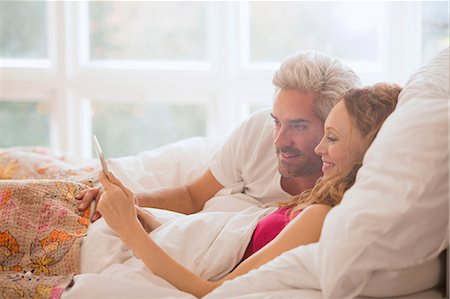 simsearch:6113-09059294,k - Couple relaxing laying in bed using digital tablet Foto de stock - Sin royalties Premium, Código: 6124-08820713