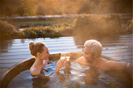 Couple toasting champagne glasses soaking in hot tub on autumn patio Foto de stock - Sin royalties Premium, Código: 6124-08820711