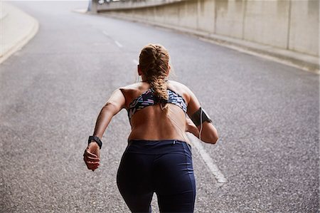 Fit female runner with mp3 player armband running on urban street Stock Photo - Premium Royalty-Free, Code: 6124-08820817