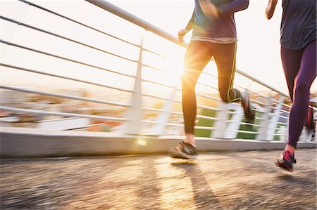 Runner couple running on sunny urban footbridge at sunrise Foto de stock - Sin royalties Premium, Código: 6124-08820837