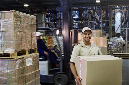 simsearch:6124-08820937,k - Portrait smiling worker carrying cardboard box at distribution warehouse loading dock Foto de stock - Royalty Free Premium, Número: 6124-08820962